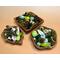 Examples of three handmade acacia bowls displaying a green and natural colored blend of botanicals. Bowl shapes are square, leaf, and flare.